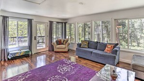 Un salón amplio con un gran ventanal, un sofá, un sillón y una alfombra morada.