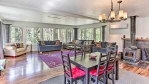Un salón comedor amplio, con ventanas grandes, chimenea y candelabro.