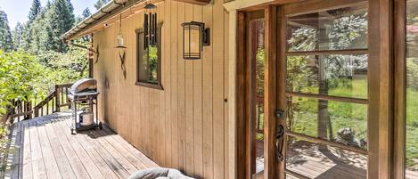 A wooden deck with a dog bed, a grill, and a gas tank.