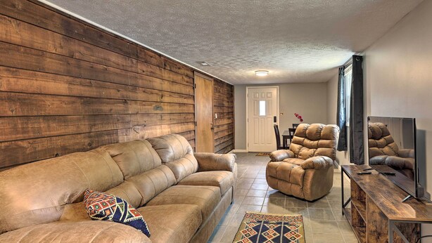 Un salon avec un mur en bois, un canapé en cuir marron, un fauteuil en cuir marron et une table basse en bois.