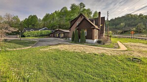 Une maison à deux étages, construite en briques, avec un toit en pente, une cheminée et une allée menant à une entrée fermée par un portail.