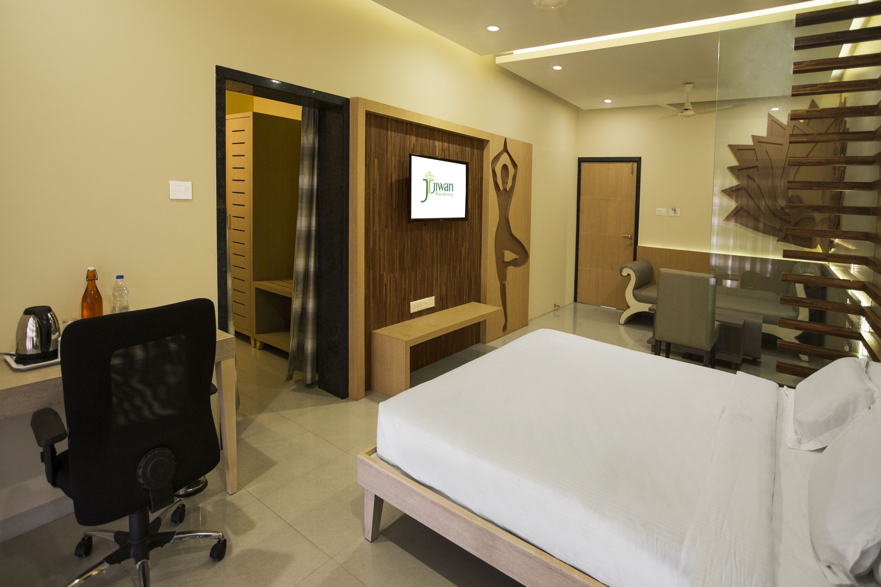 Habitación de hotel con cama, escritorio, silla y televisión instalada en la pared.