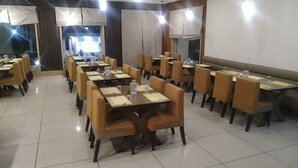 Un comedor con varias mesas y sillas, dispuestas en filas.