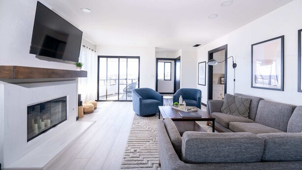 Een moderne woonkamer met een open haard, een flatscreen-televisie en een groot raam met uitzicht op de stad.