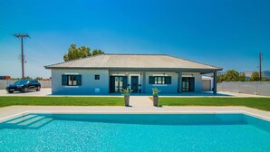 Ein zweistöckiges Haus mit Schwimmbecken davor.