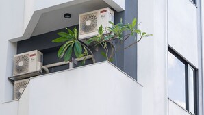 Ein modernes Gebäude mit mehreren Klimaanlagen auf Balkonen und einer Pflanze auf einem der Balkone.