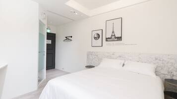 A modern hotel room with a large bed, a marble headboard, and two framed pictures on the wall.