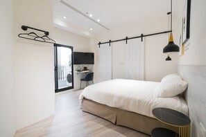 A modern bedroom with a large bed, a desk, and a chair.