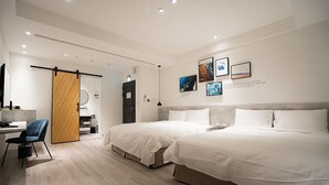 Ein modernes Hotelzimmer mit zwei Betten, einem Schreibtisch, einem Sessel und einem Kleiderschrank.