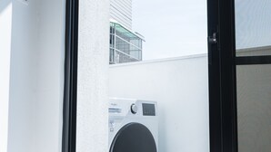 Ein modernes Zimmer mit großem Fenster, einer Waschmaschine und einer Tür.