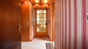 Un pasillo de madera con una puerta que da a una habitación con un amplio ventanal.