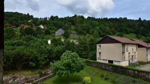 Zona residencial con casas, un muro de piedra y un área verde con un árbol y un banco de piedra.