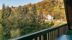 Une vue depuis un balcon donnant sur une colline, avec des maisons et une végétation dense.