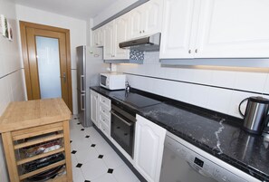 Een koelkast, een microgolfoven, een oven, kookgerei, borden en bestek