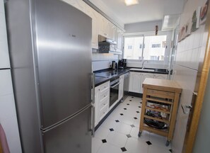 Een koelkast, een magnetron, een oven, kookgerei, borden en bestek
