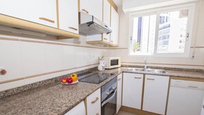 Une cuisine moderne avec des armoires blanches, des comptoirs en granit, un four à micro-ondes et un lave-vaisselle.