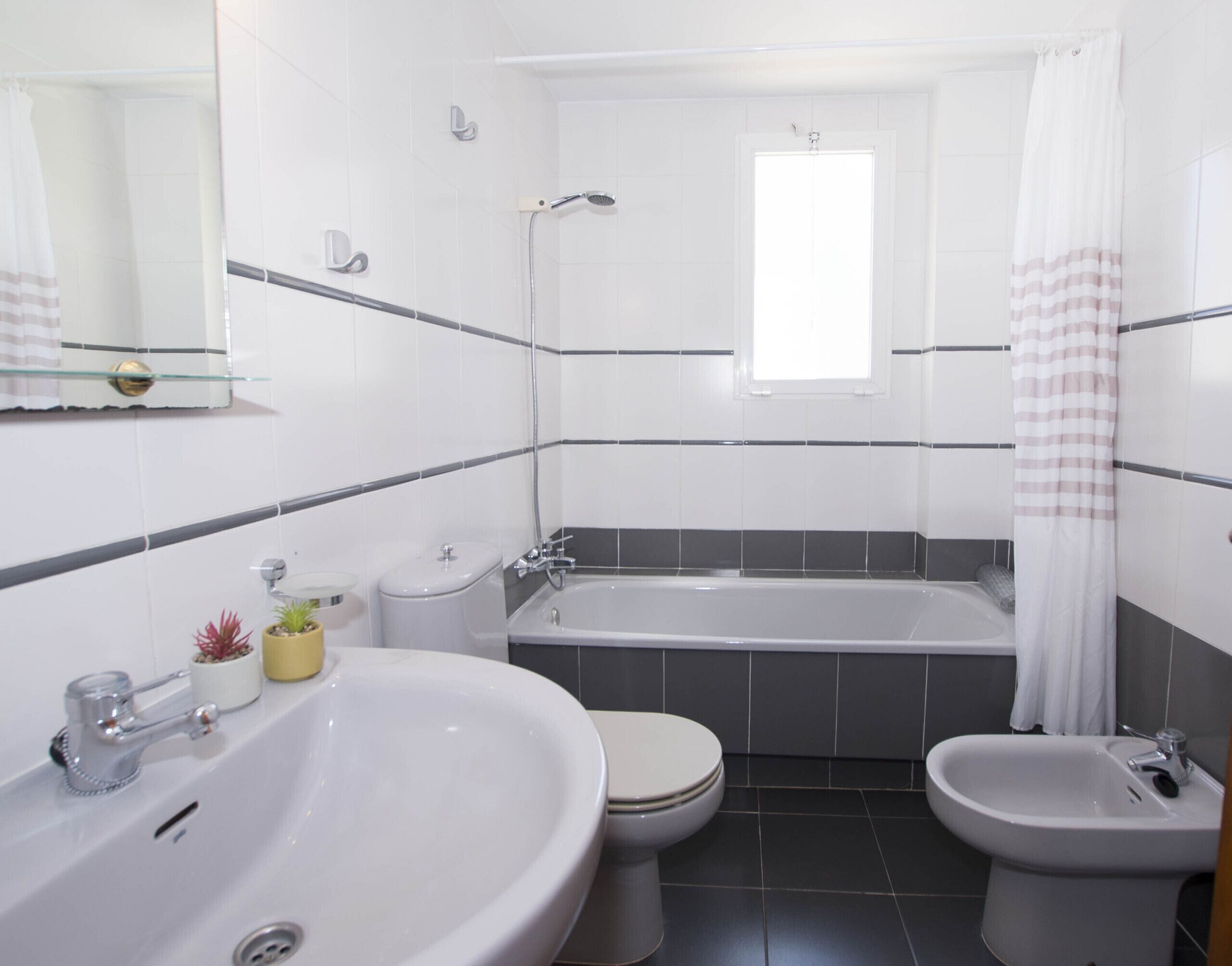 Et moderne badeværelse med badekar, to toiletter, en bidet og en stor vask.