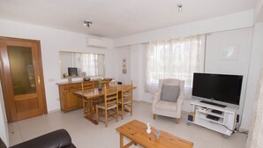 Un salon comprenant un canapé, une table basse, un téléviseur et un coin repas.