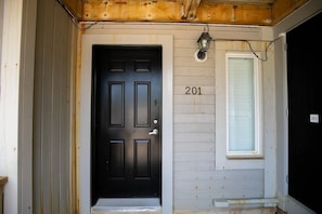 Welcome to residence 201, featuring a classic entrance with a black door and a white-framed window.