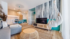 Ein modernes Wohnzimmer mit einer Couch, einem Fernseher und einem Hängekorbsessel.
