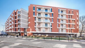 Ein modernes Mehrfamilienhaus mit Backsteinfassade, Balkonen und einem geschlossenem Eingangsbereich.