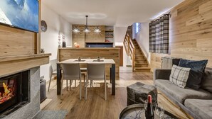 Ein zeitgemäßer Wohnraum mit Kamin, Essbereich, Küche und Treppe.