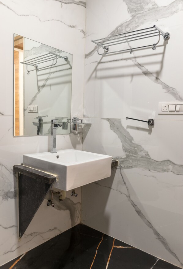 A bathroom with a white sink, a mirror, and a towel rack.