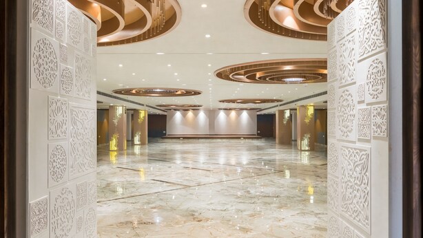 Un vestíbulo amplio con piso de mármol, paneles decorativos en las paredes y un diseño moderno de techo con lámparas circulares.