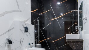 Un baño moderno con inodoro blanco, lavabo redondo y espejo.