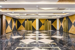 A spacious room with a polished marble floor, geometric wall patterns, and recessed lighting. - Meridian hotel Banquets and Rooms (Surat)