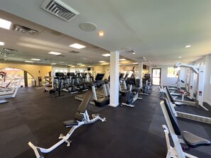 A gym with treadmills, elliptical machines, and weight stations.