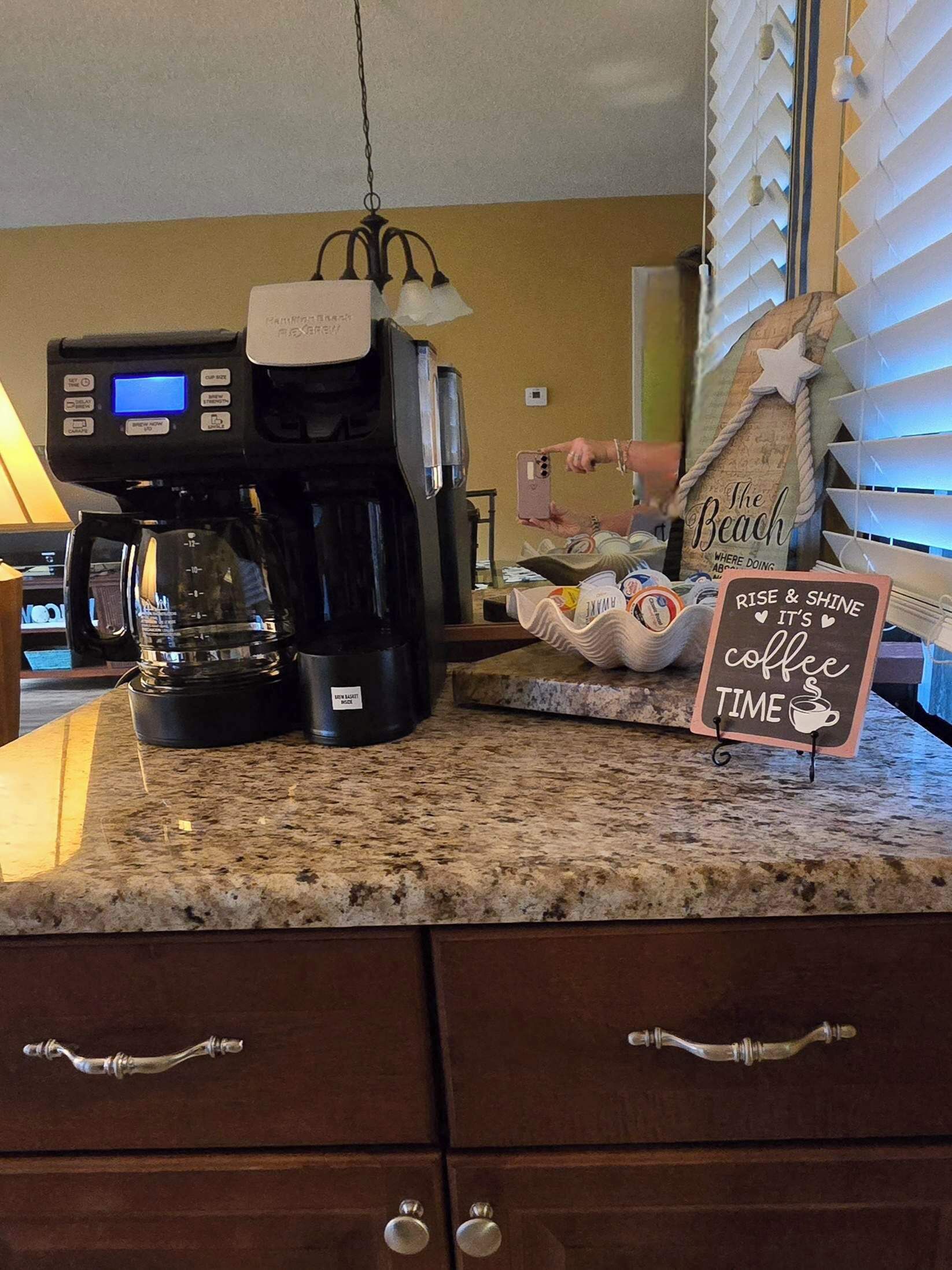 Una cafetera sobre una encimera de cocina, con un cartel que dice 'Rise & Shine It's Coffee Time'.