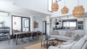 Un salon moderne avec un canapé gris, une table basse et un coin repas comprenant des chaises et une table.