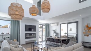 Un salon moderne comprenant un ensemble de canapés, une table à manger avec des chaises et un coin cuisine avec une télévision et une cheminée.
