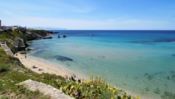 A coastal beach with clear waters, a sandy shore, and a rocky outcrop with vegetation. - Casa dei Mori by Interhome (Terrasini)