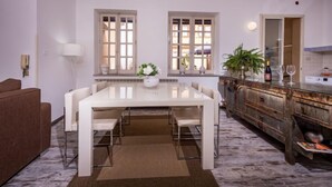 A modern kitchen with white cabinetry, a marble countertop, and a dining area with a white table and chairs. - Casa dei Mori by Interhome (Terrasini)