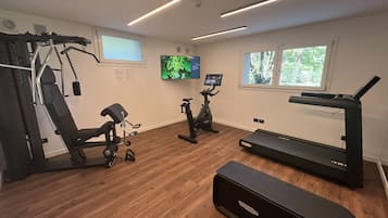 A home gym with a treadmill, stationary bikes, and a weight machine.