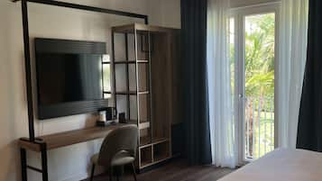 Une chambre d’hôtel moderne dotée d’un grand lit, d’un bureau avec une chaise, d’une télévision et d’une porte coulissante donnant sur un balcon.