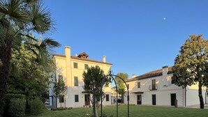 A courtyard with a stone fountain, surrounded by well-maintained grass and flowering plants. - The Foscarini (Mogliano Veneto)