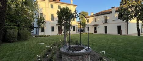 A courtyard with a stone fountain, surrounded by well-maintained grass and flowering plants.