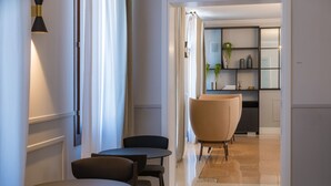 A hallway with a dining area featuring round tables and chairs, a carpeted floor, and a bookshelf with decorative items. - The Foscarini (Mogliano Veneto)
