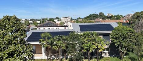 A residential area with solar panels on a building, a well-maintained lawn, and surrounding trees.