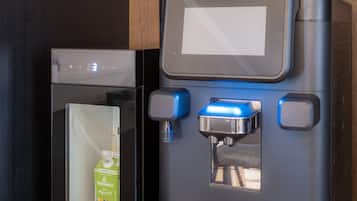 A coffee machine with a milk frother and a milk dispenser, a coffee grinder, and a glass container with coffee beans.