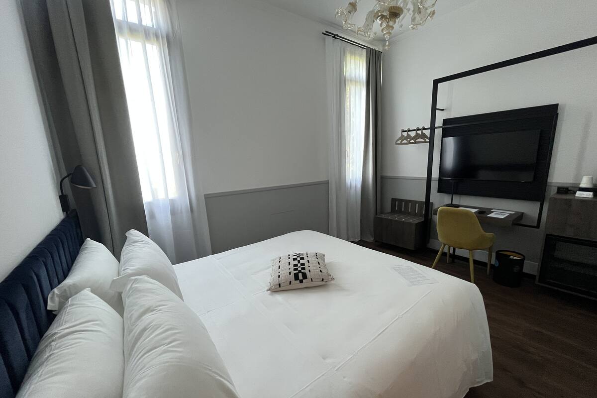 Ein Hotelzimmer mit Bett, Fernseher, Schreibtisch und Stuhl.