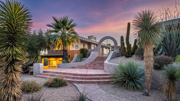 Un bâtiment de style désertique doté d’un patio, de palmiers et de cactus.