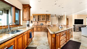 Une cuisine spacieuse dotée de meubles en bois, de plans de travail en granit et d’un îlot central.