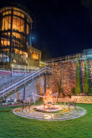 A stone building with a circular glass enclosure, a fire pit, and outdoor seating. - Kanishka Retreat Resort Chail (Kandaghat)