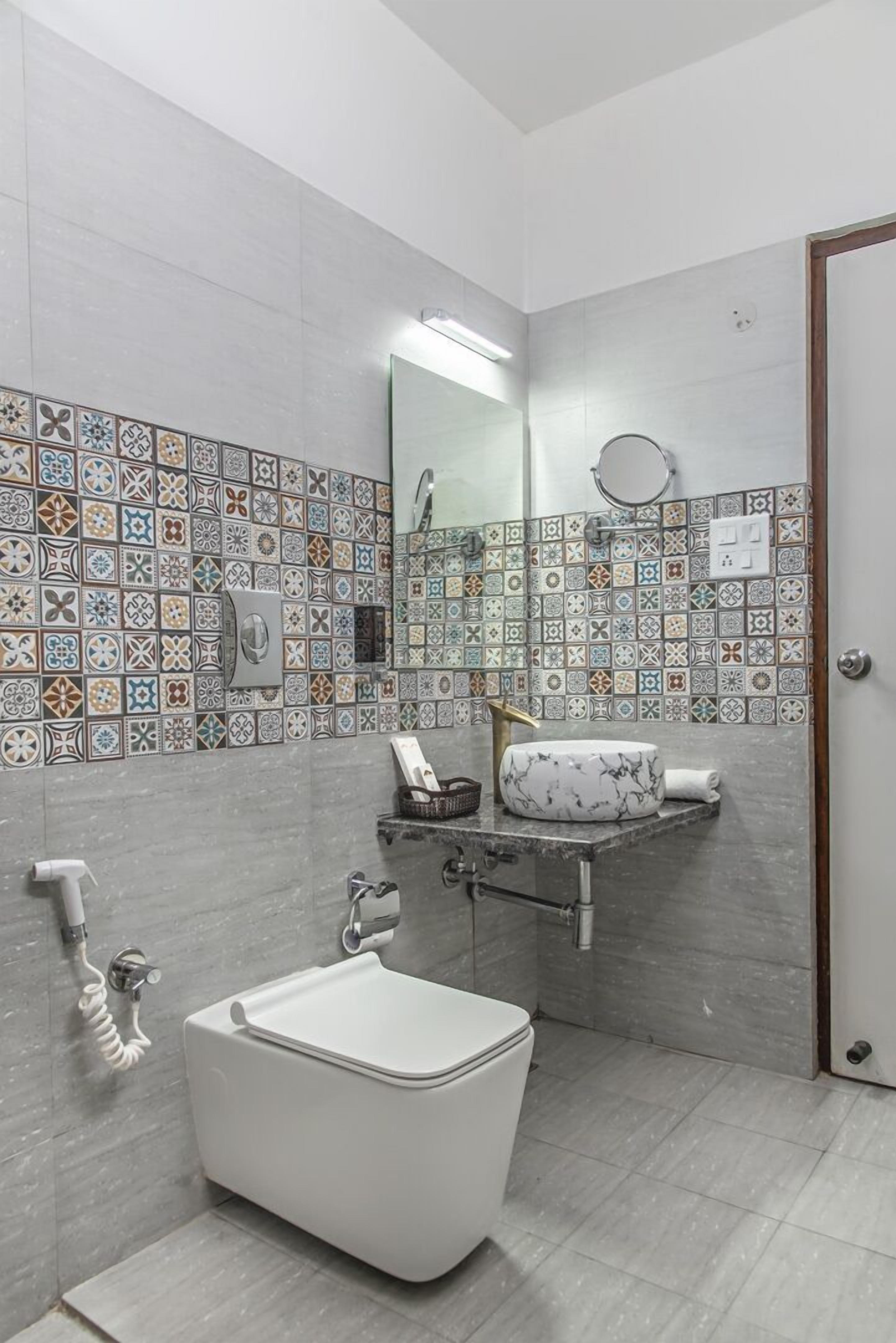 A bathroom with a white toilet, a sink with a marble basin, and a shower area.