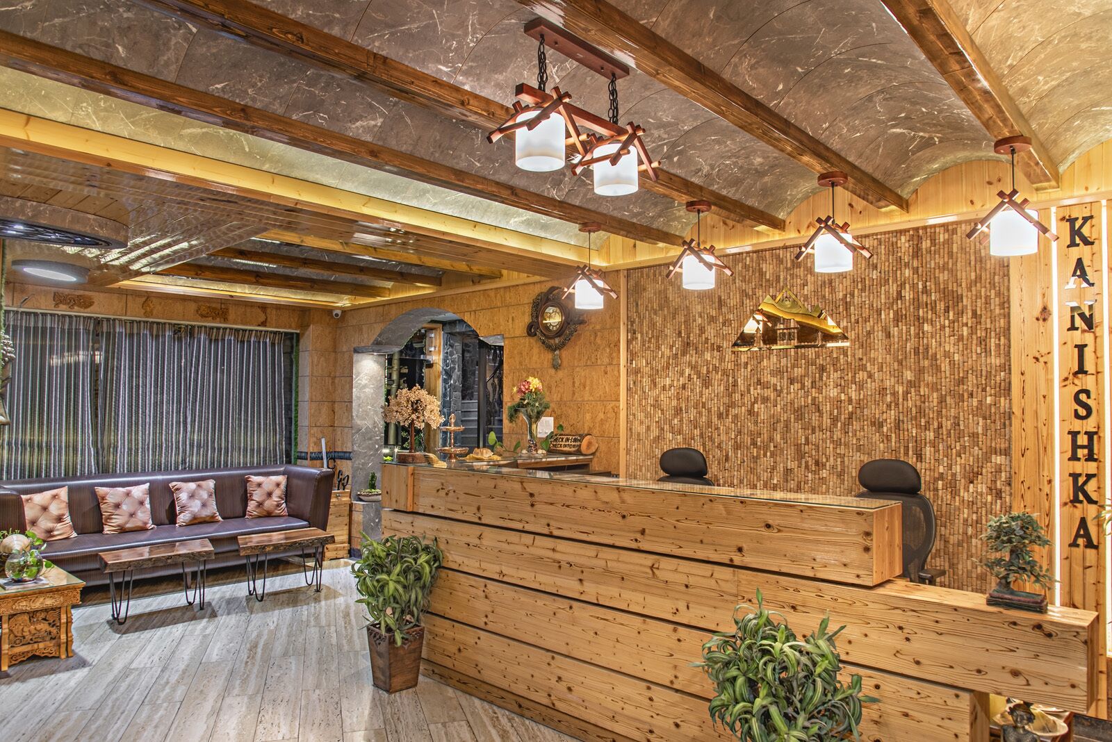A reception area with a wooden reception desk, a sofa, and potted plants.