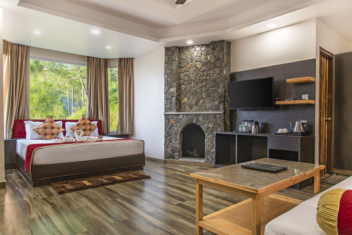 Une chambre avec une cheminée en pierre, un téléviseur fixé au mur et une table basse en bois.